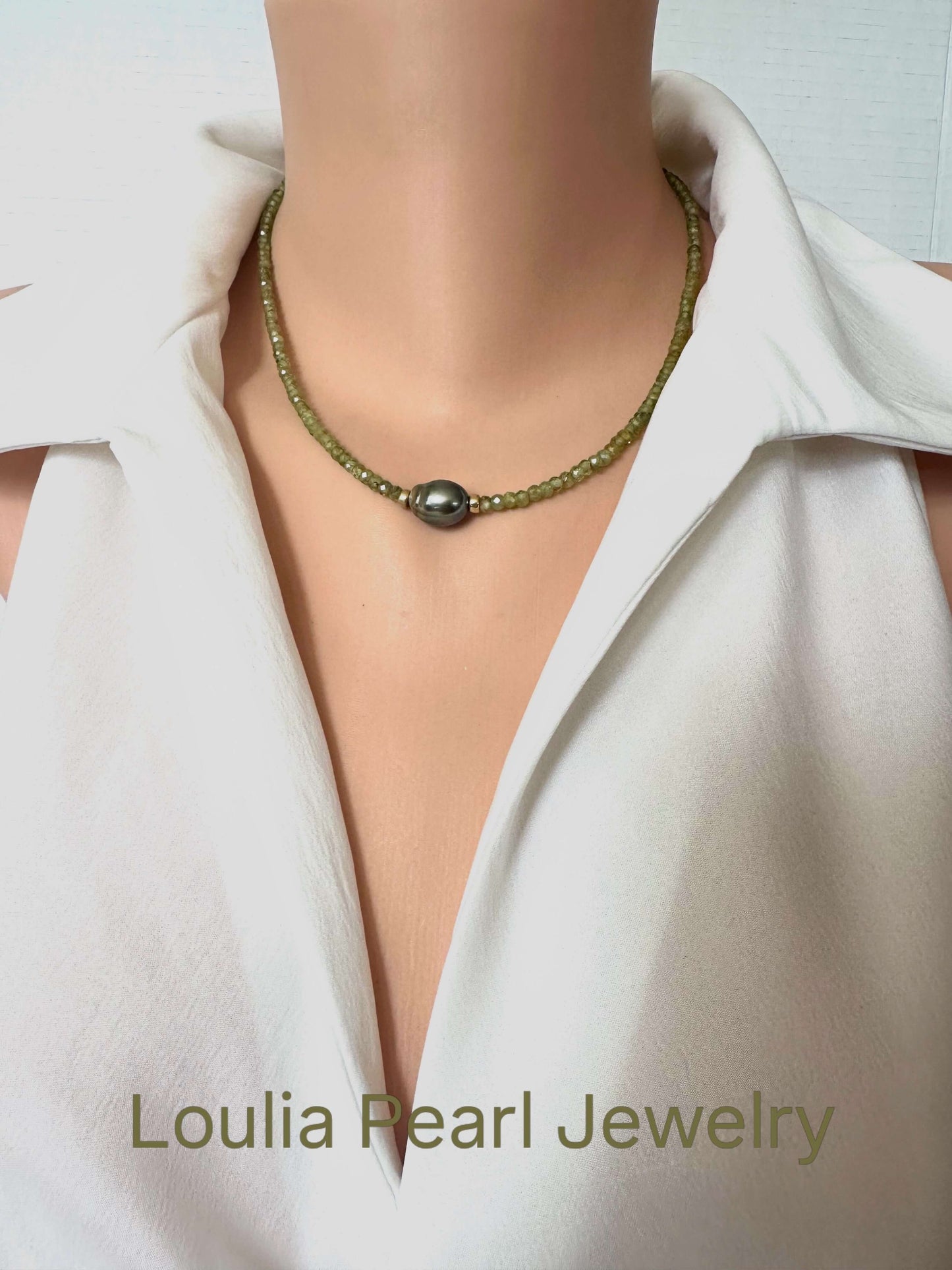 A close-up of a model wearing a beaded necklace with a central dark gray pearl, styled with a white collared shirt. The text 'Loulia Pearl Jewelry' is visible at the bottom.