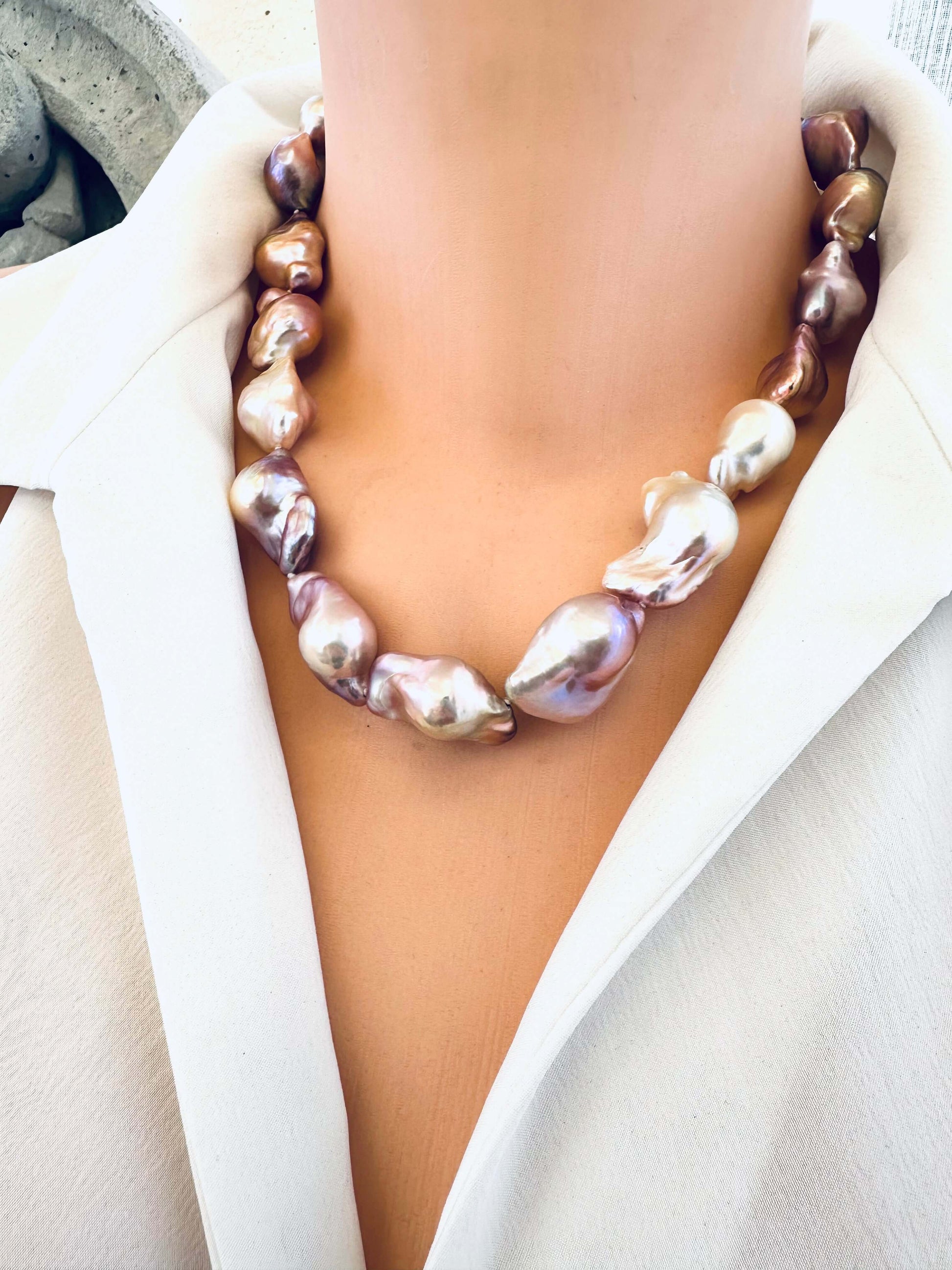 Pearl necklace worn by a person in a white outfit