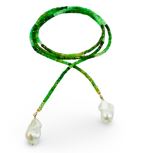 A beaded necklace featuring vibrant green faceted beads and two large, irregular white baroque pearls suspended from gold-toned rings, set against a solid white background.