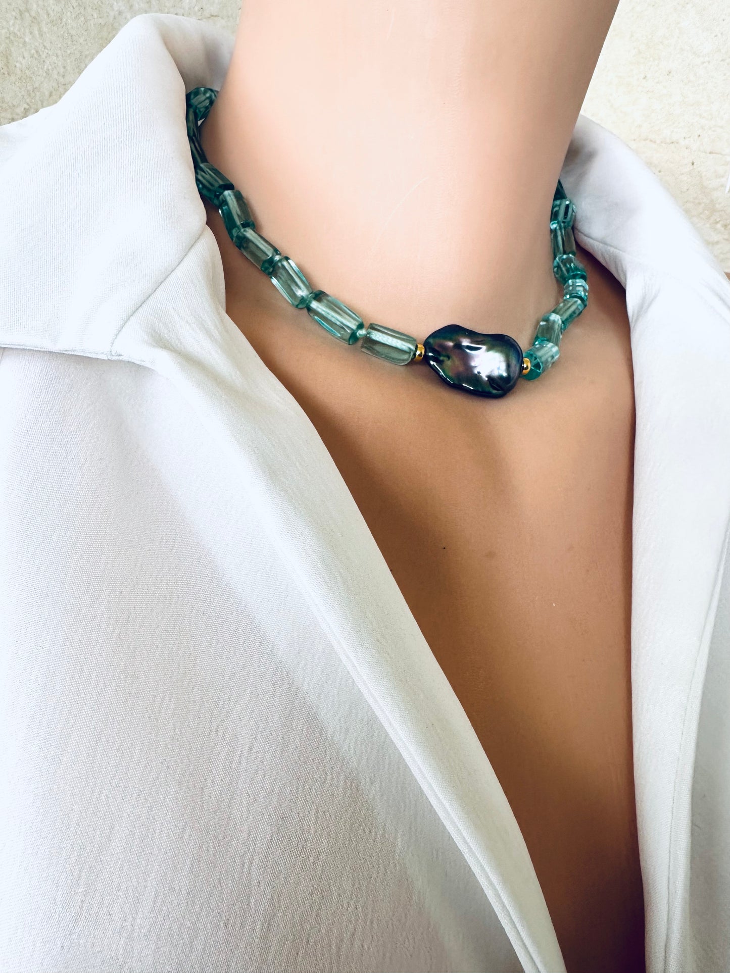 Green beaded necklace worn by a person in a white outfit
