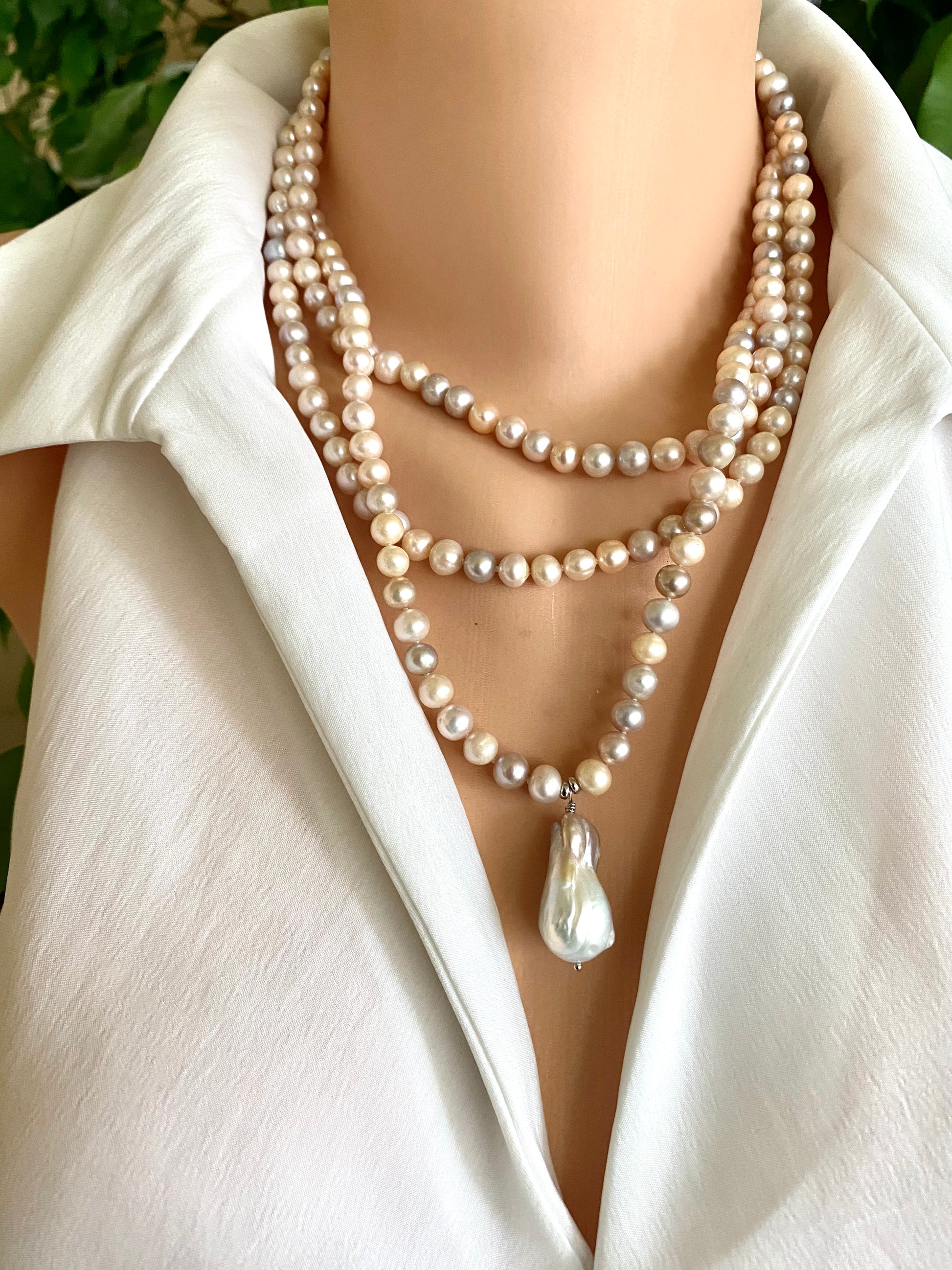 Pearl necklace with a large white pearl pendant on a white outfit.