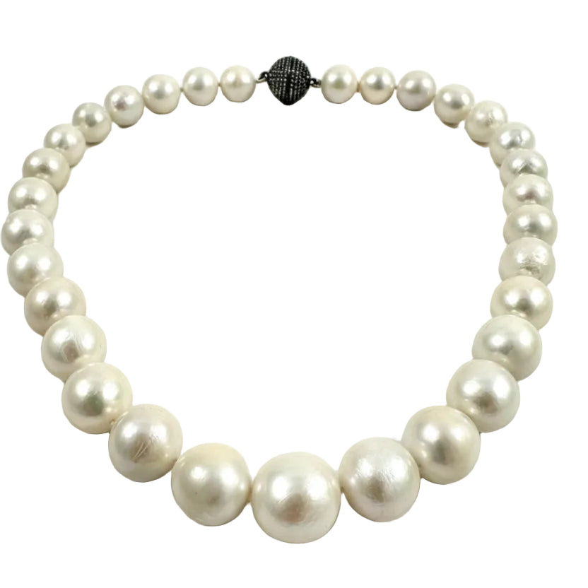 A strand of white freshwater pearls arranged in a circle on a light gray background, featuring a textured black clasp at the top.