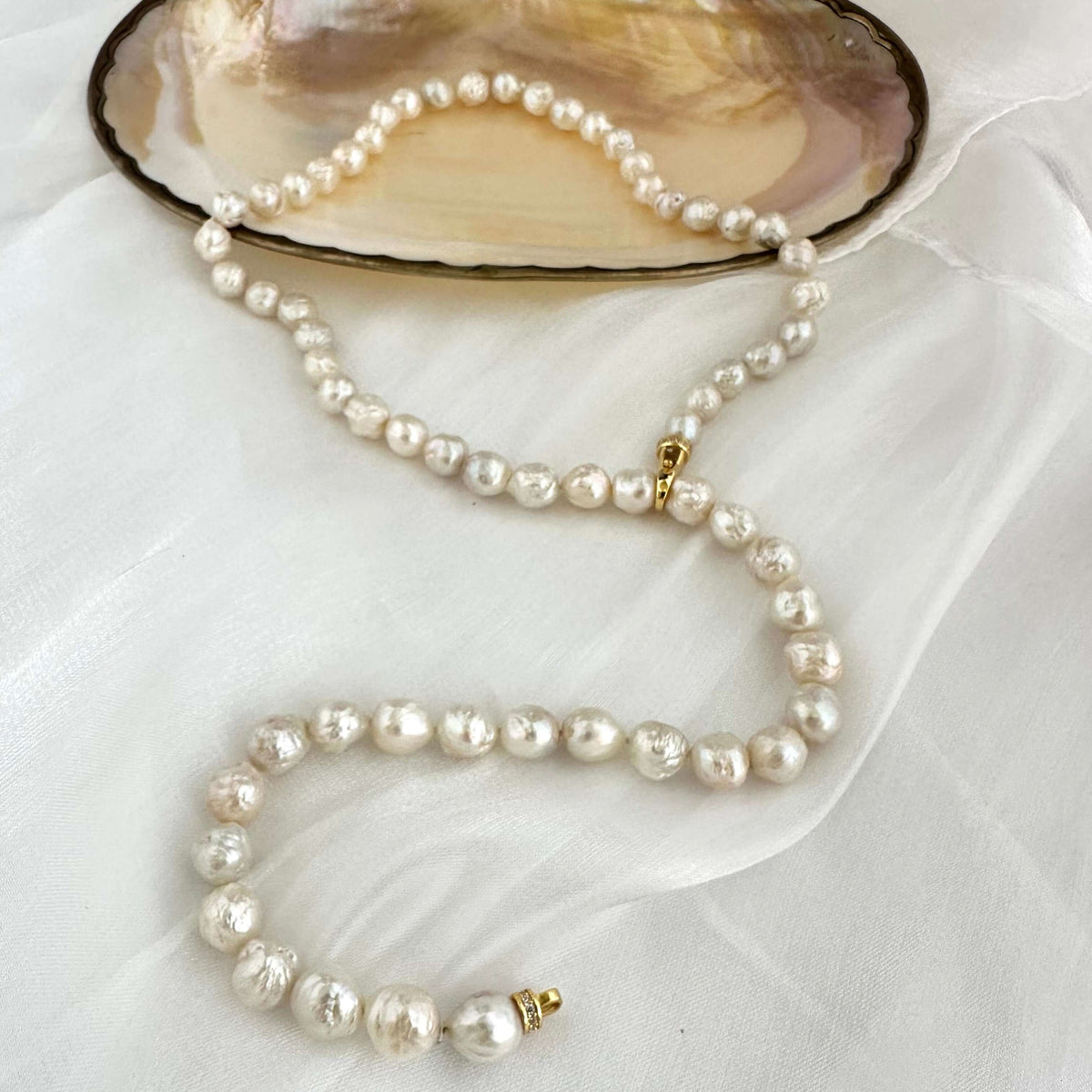 Edison pearl Y necklace featuring organic baroque pearls displayed on an elegant shell plate.