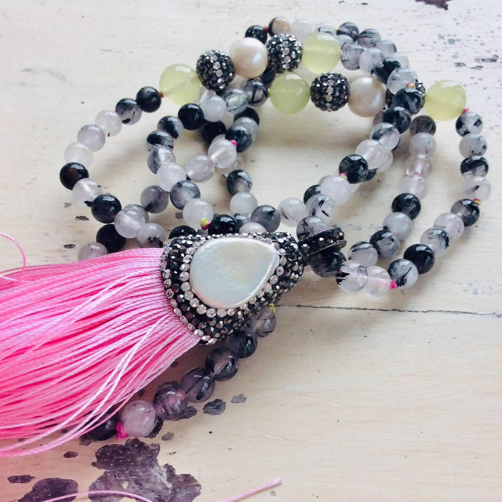 Boho rutilated quartz necklace featuring pearls and rhinestone accents on white background.