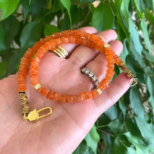 Carnelian choker necklace featuring vibrant orange gemstone beads, elegantly showcased in a person's hand.