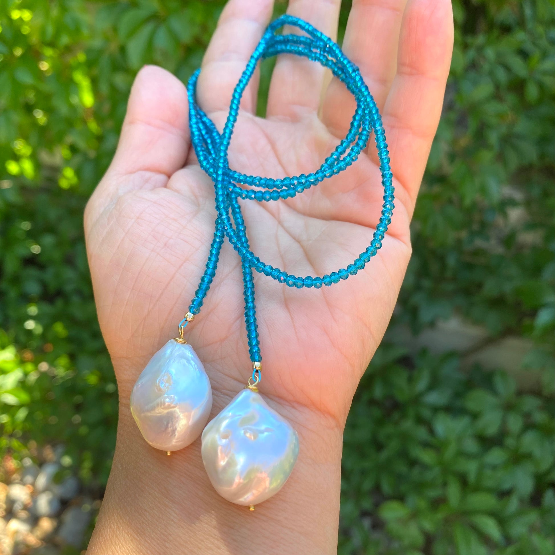 London Blue Quartz Lariat Necklace in hand against greenery, two baroque pearl ends close-up