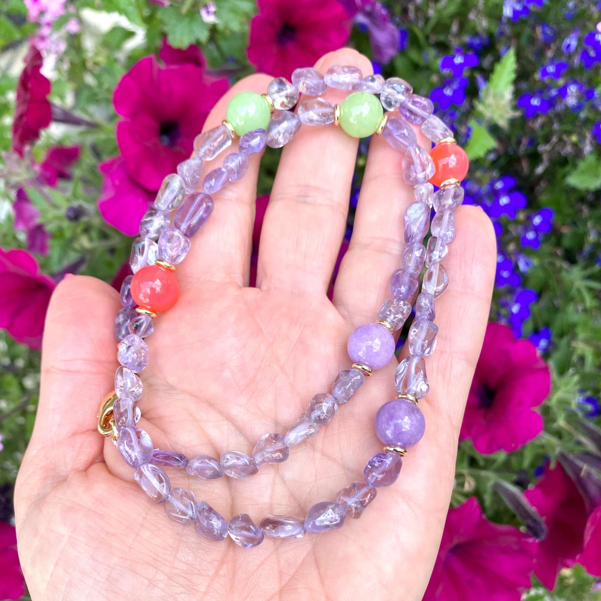 Amethyst gemstone necklace in hand with flowers, light amethyst nuggets and colorful gemstone beads