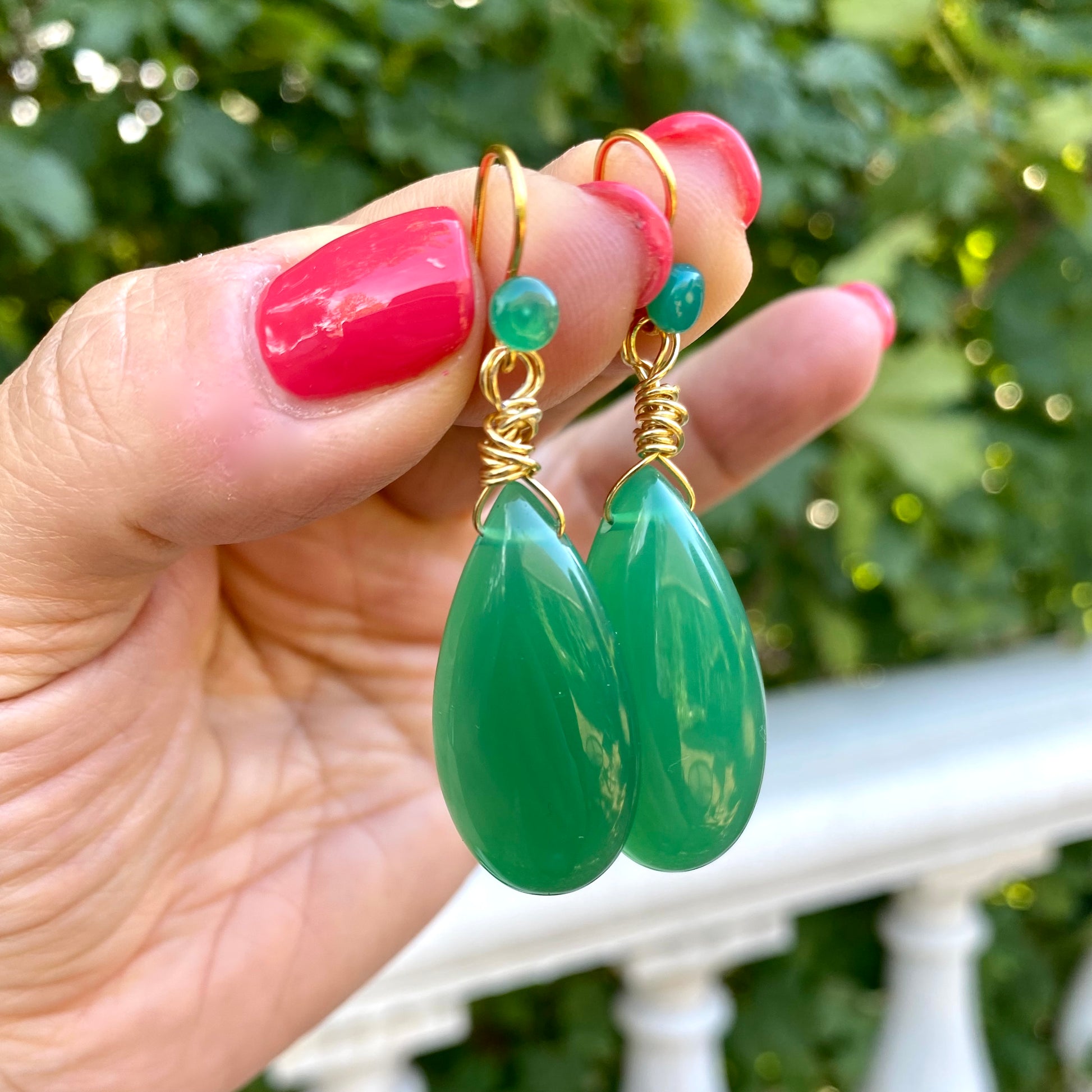 Emerald green onyx teardrop earrings held in hand showing vibrant green color