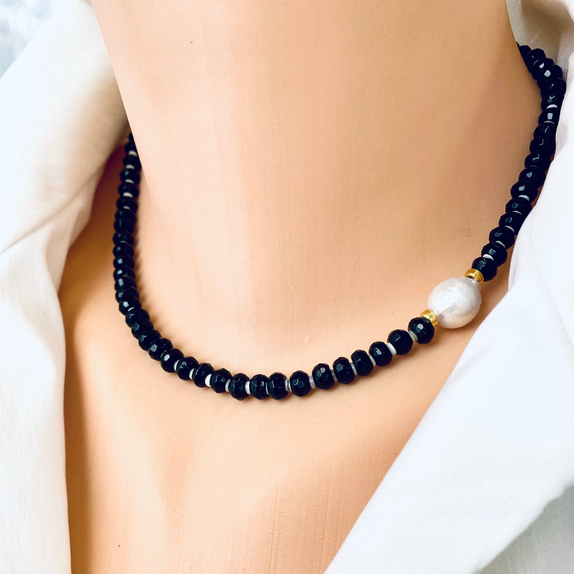 Black onyx pearl choker necklace worn at the neckline with white baroque pearl accent