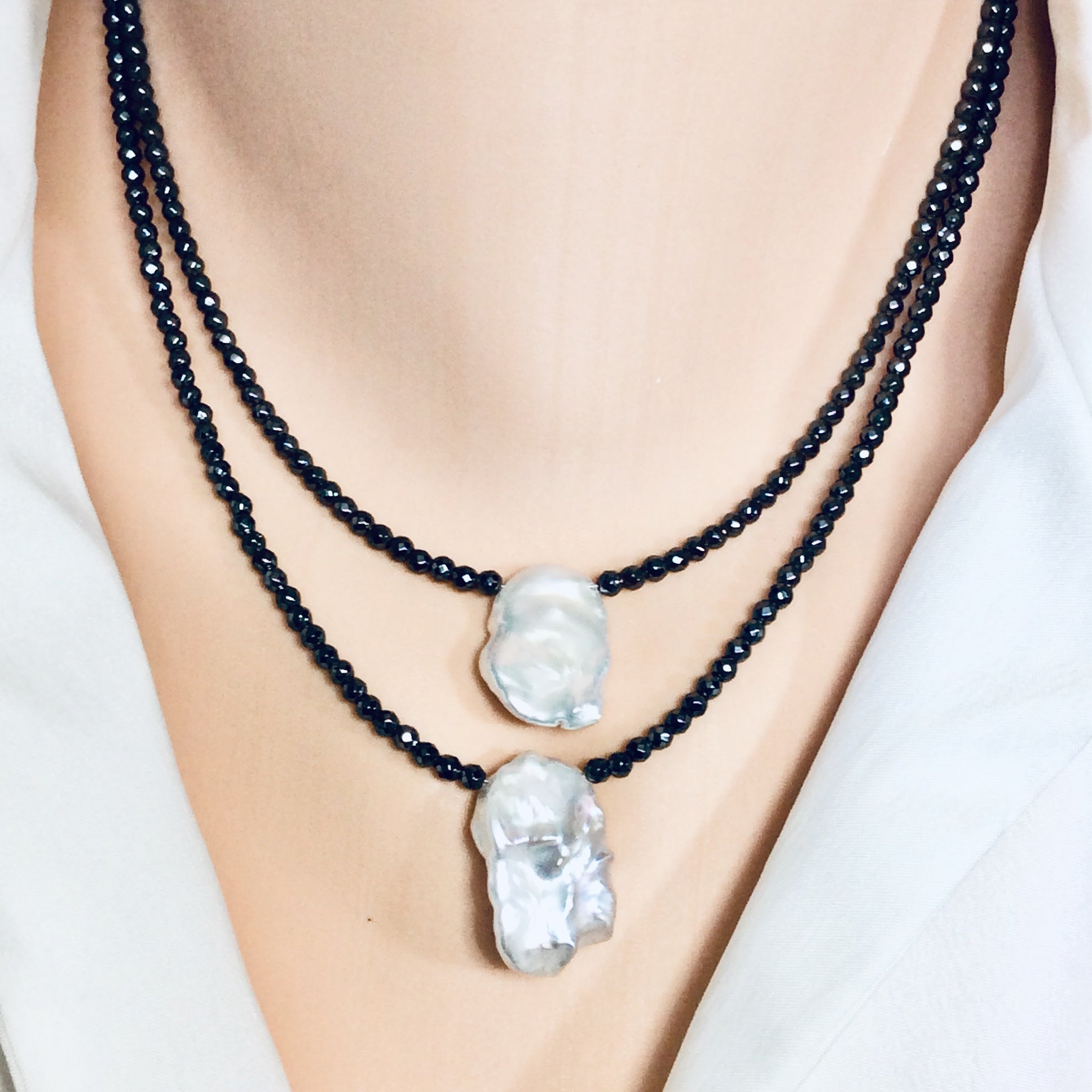 Hematite baroque pearl short necklace worn on model layered with another necklace at the collarbone