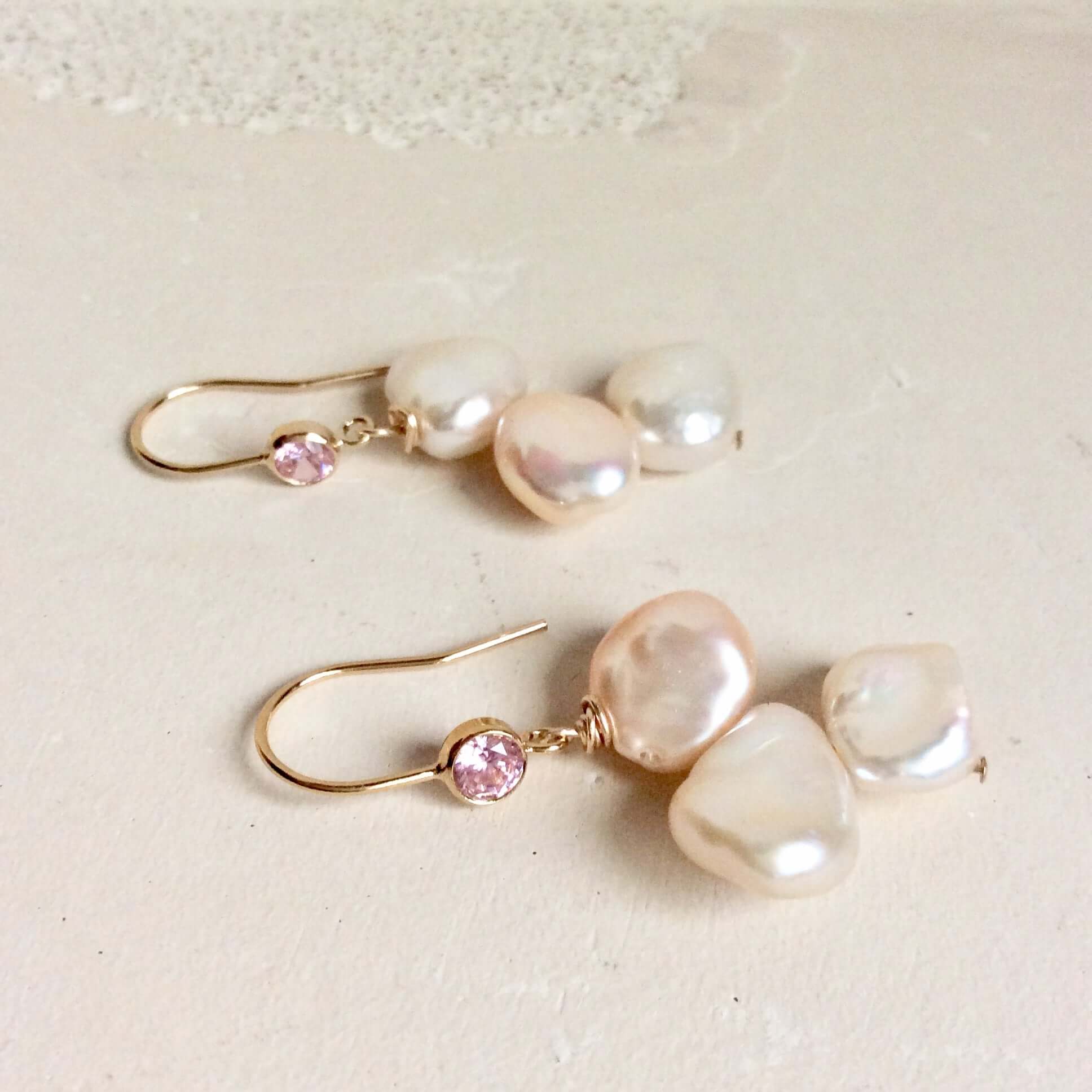 Elegant earrings composed of Natural Keshi pink and white pearls hanging from gold filled hooks with pink cubic zirconia bezel
