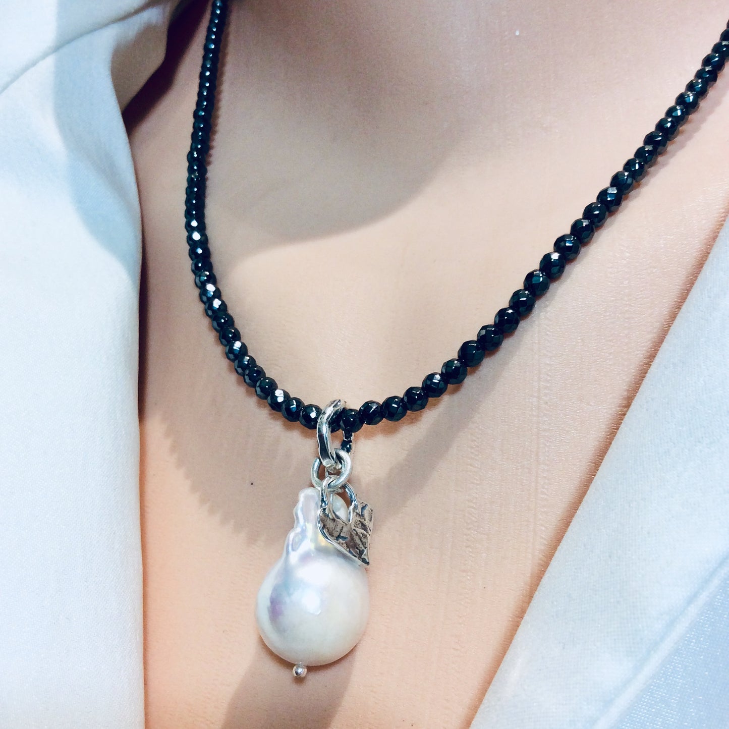 Hematite necklace with baroque pearl pendant close-up highlighting pearl and silver heart charm