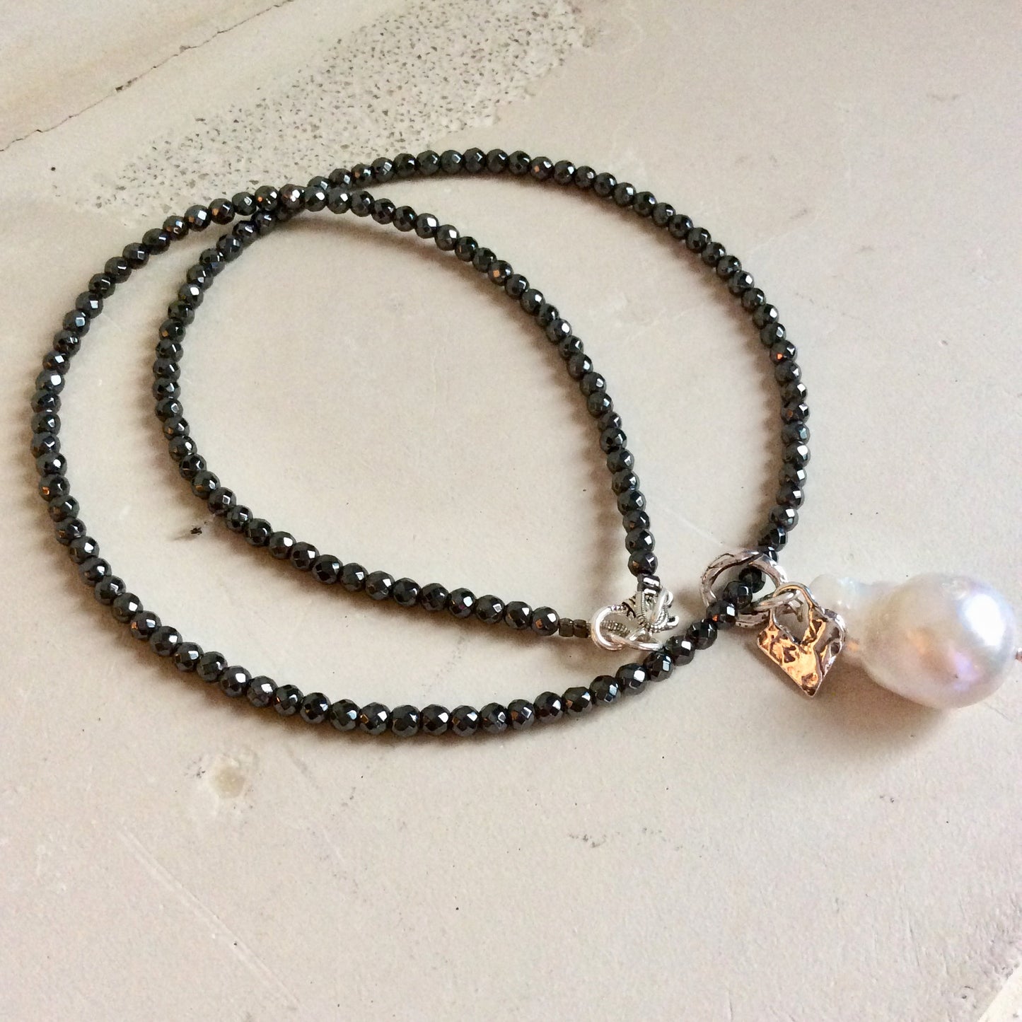 Hematite necklace with baroque pearl pendant showing floating pearl and charm detail