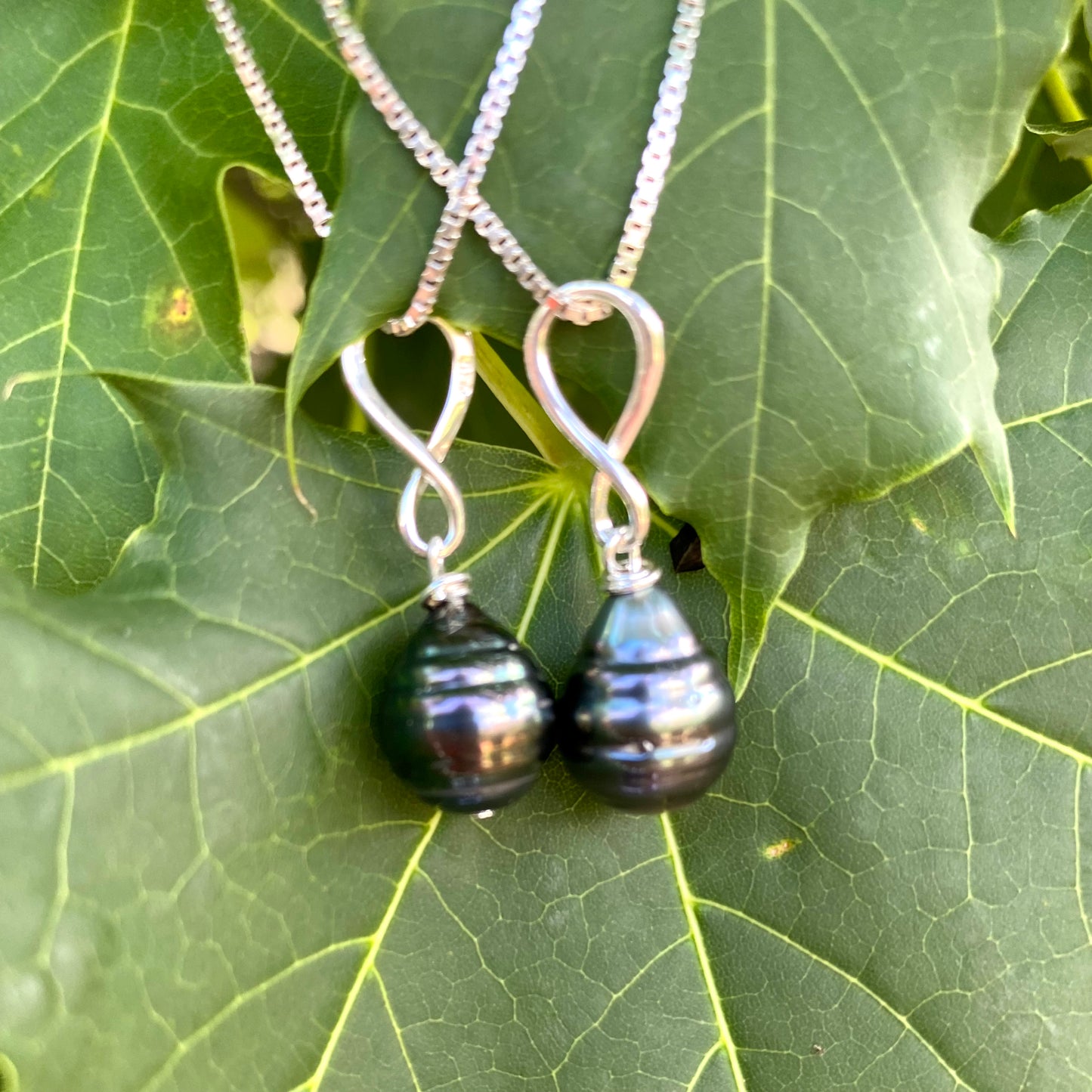 Tahitian teardrop pearl pendant box chain on leaf background, sterling silver pendant with dark Tahitian pearl