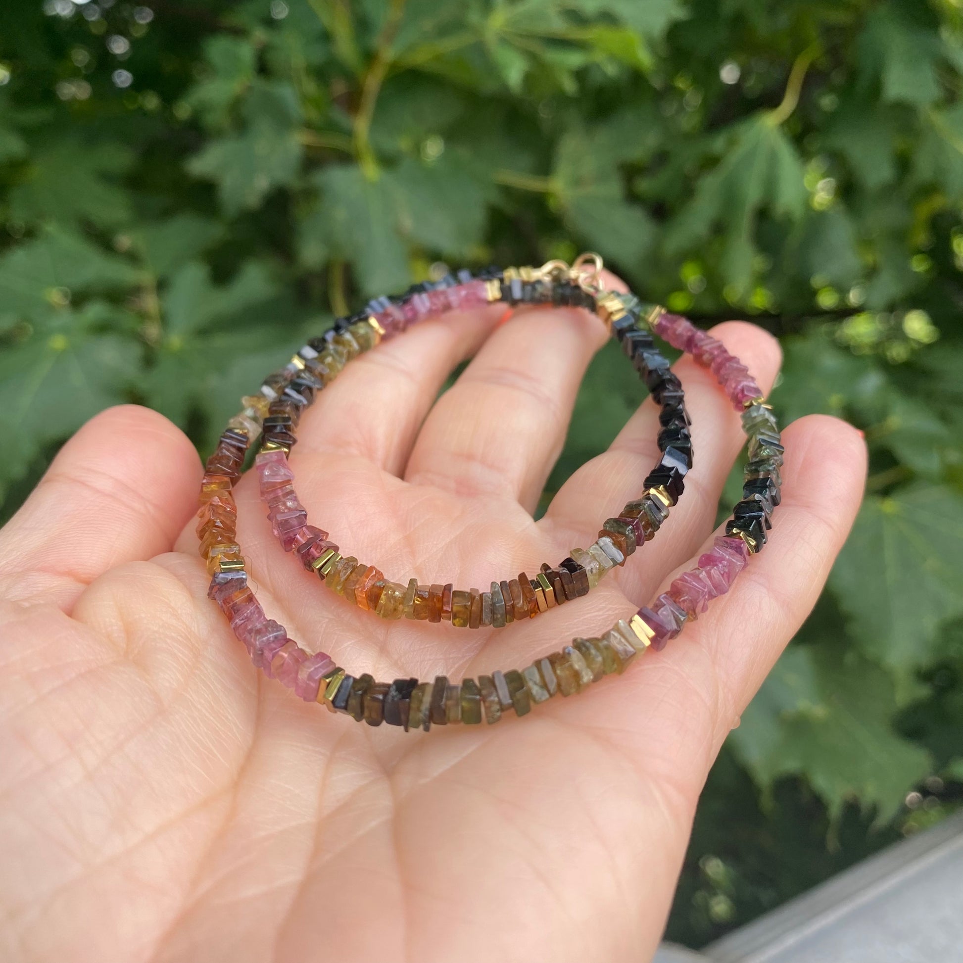 Tourmaline Necklace 14k Gold Filled coiled in hand against greenery, bead detail close-up