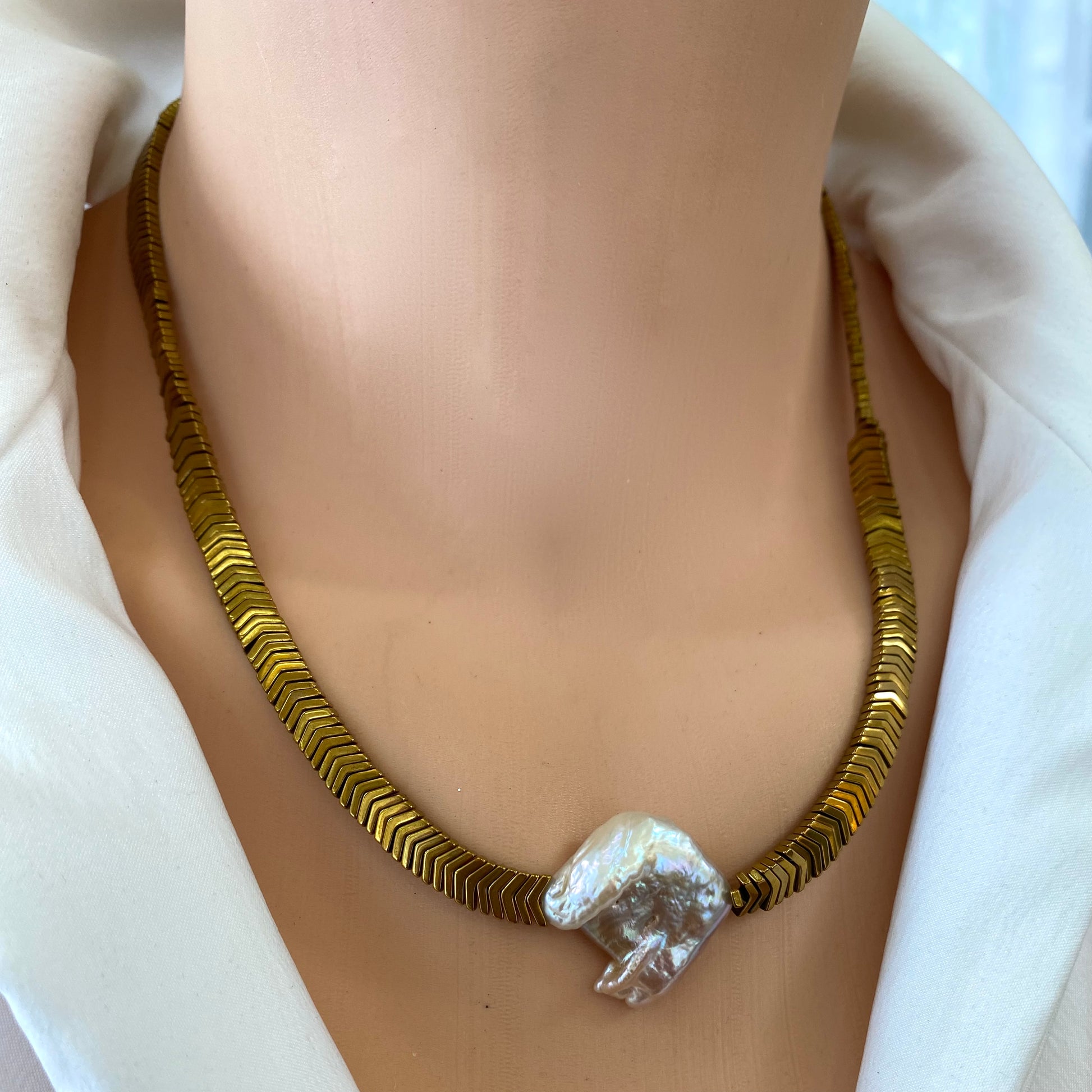 Gold hematite keshi pearl necklace styled at the collarbone with bold metallic finish