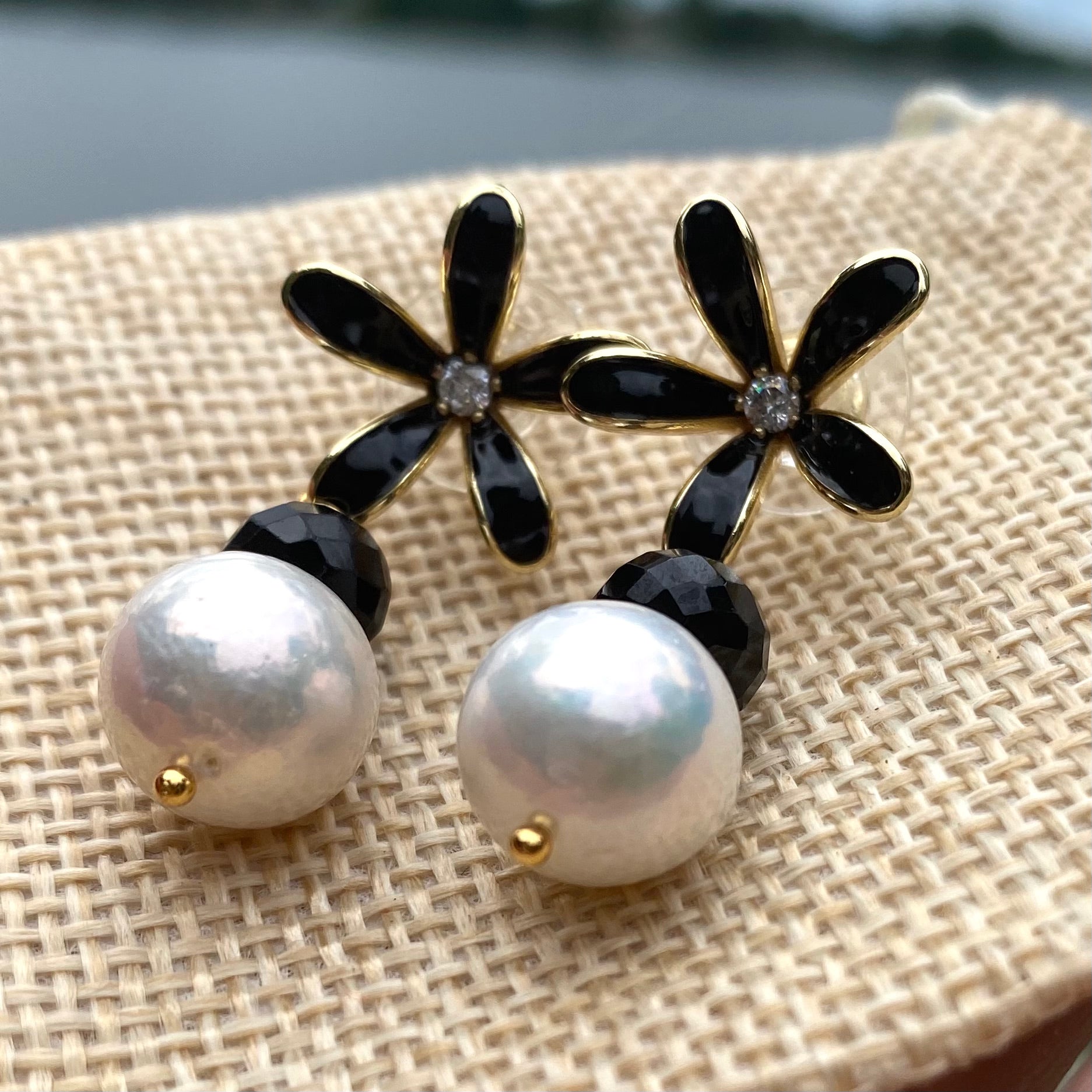 Edison pearl black spinel earrings close-up on beige fabric, near-round Edison pearls with black flower studs