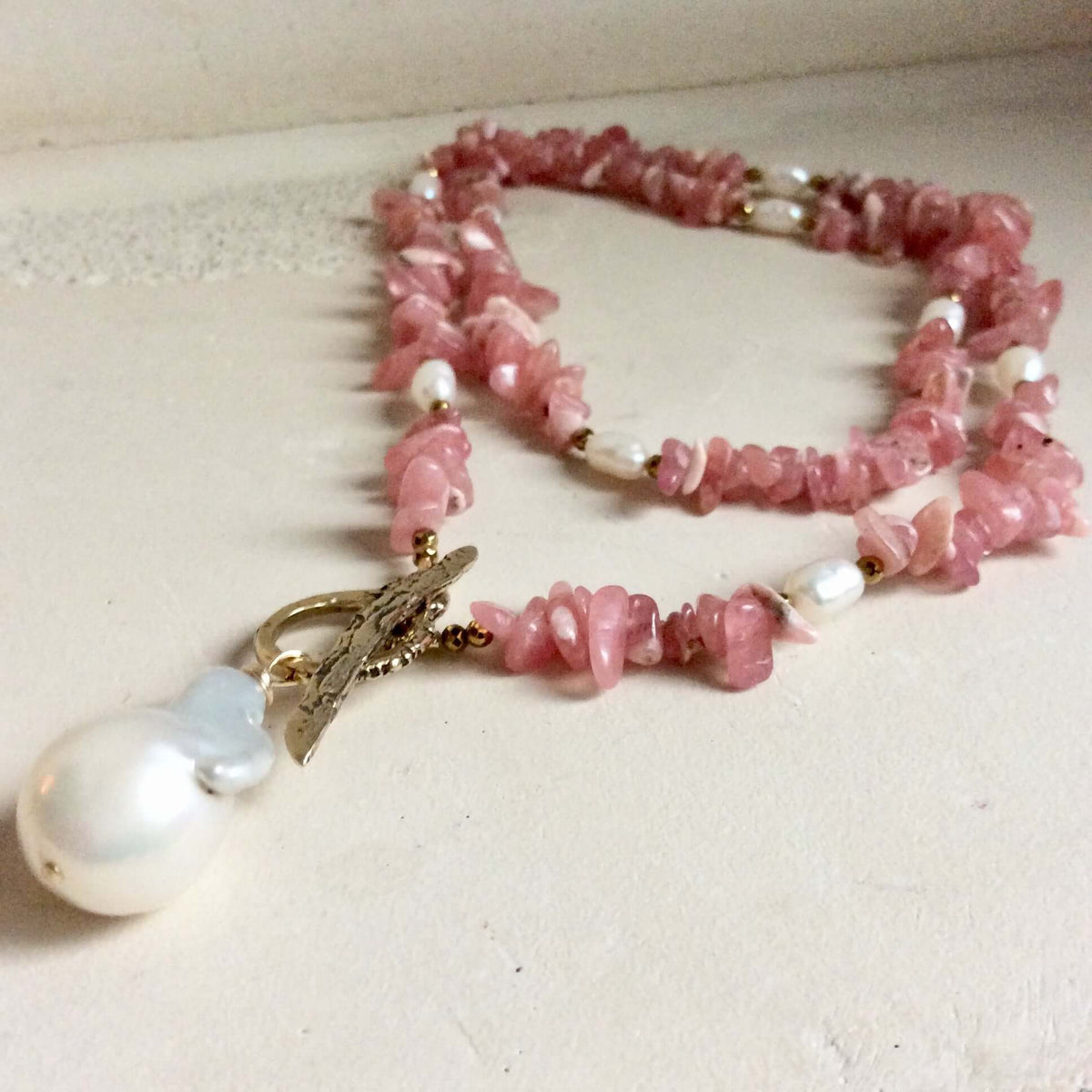Rhodochrosite pearl toggle necklace displayed flat highlighting gold hematite beads and pearls