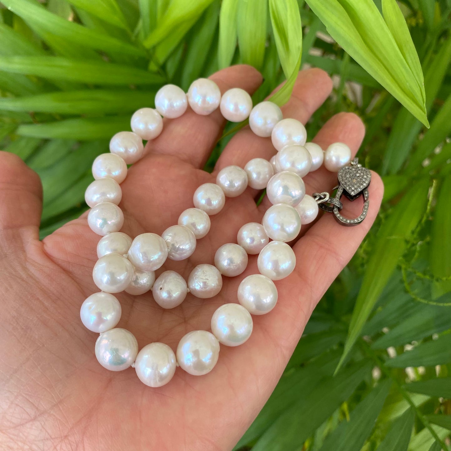 Edison pearl necklace with heart pavé diamond clasp, showcasing luxurious freshwater pearls in a hand-held display.