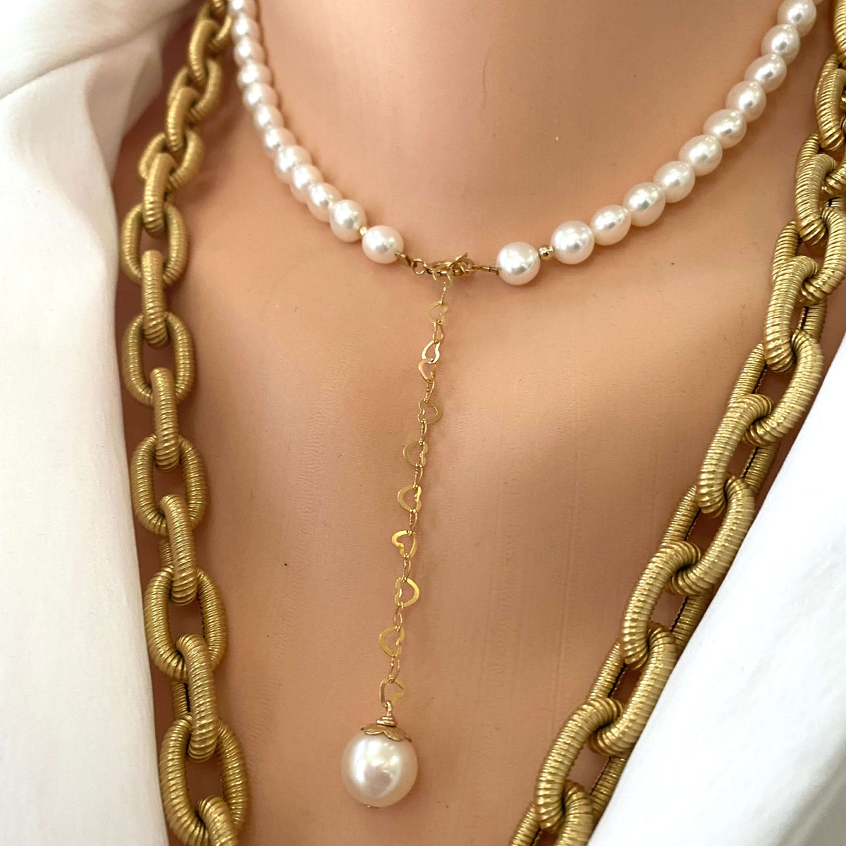 Pearl heart necklace layered with gold chain showing pearl charm and heart chain detail